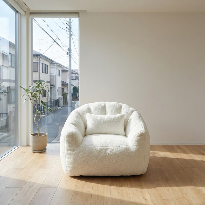 Cream bag japanese bean chair with lumbar pillow on light wood flooring near window overlooking residential neighborhood