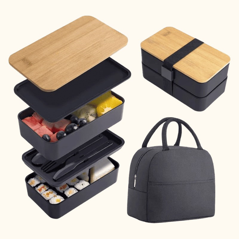 Exploded view of black bento box japanese containers with bamboo lid showing stacked compartments filled with sushi and fruit beside insulated carrying bag