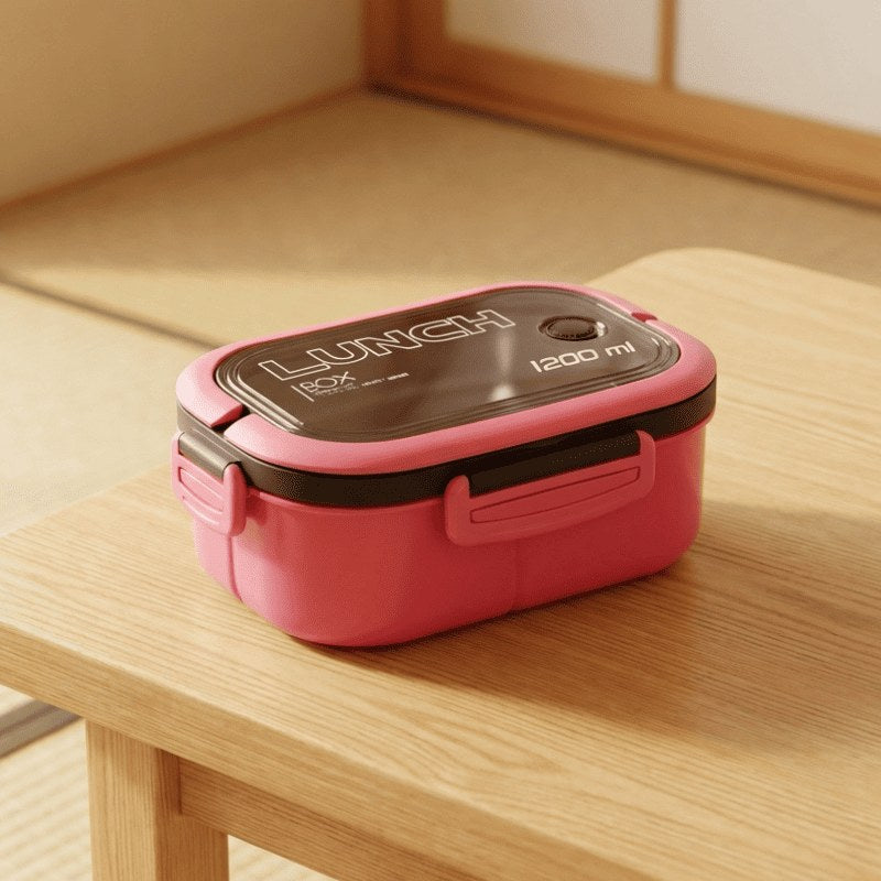 Pink bento box lunch box with transparent window lid and secure clasps sitting on natural wood table in minimalist room with soft afternoon sunlight