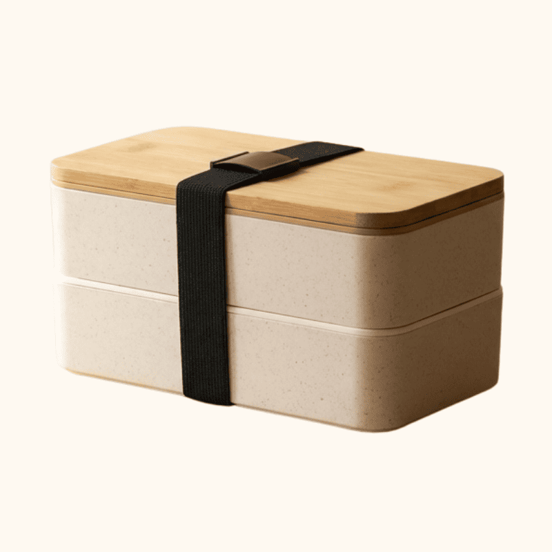 Double-layer beige bento japanese box lunches with bamboo lid and black elastic band on neutral studio background