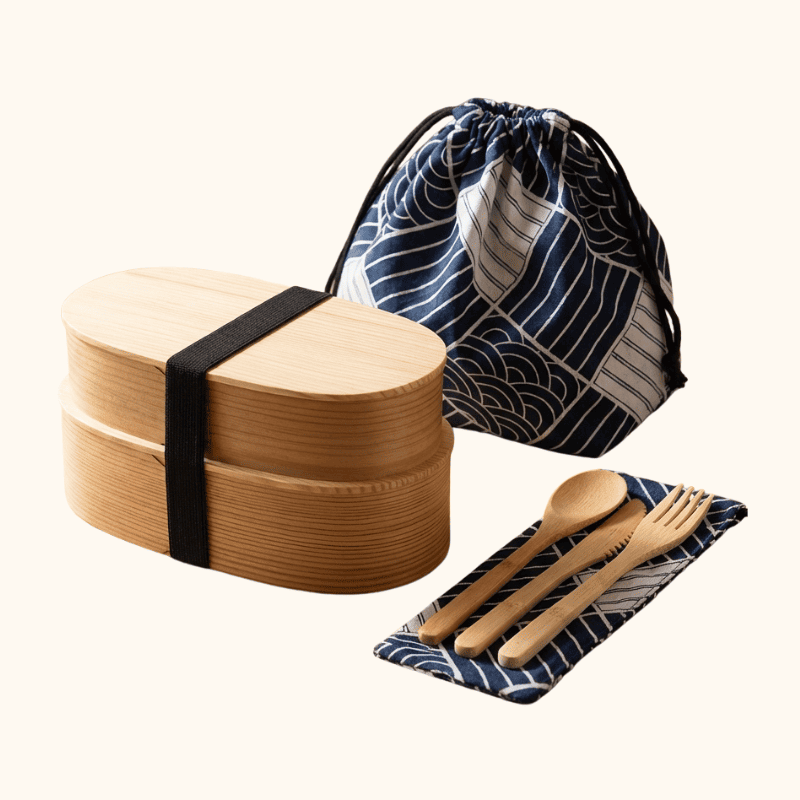 Two-layer natural wood bento japanese food box with large drawstring bag and matching wooden utensils on white studio background