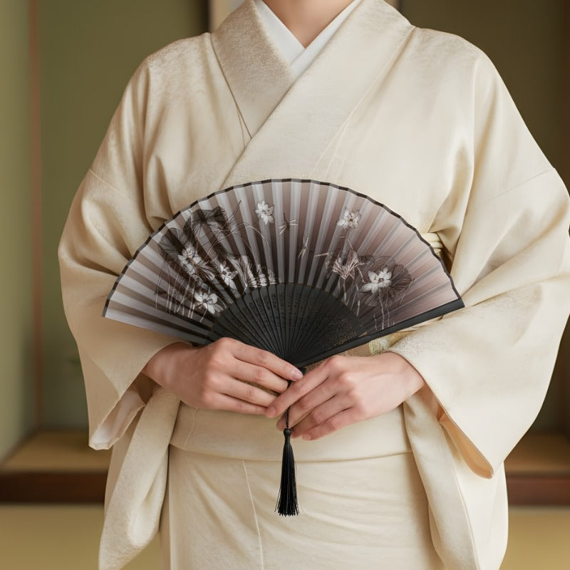 Person in cream kimono holding black japanese fan with twilight gradient and white iris pattern in traditional interior setting