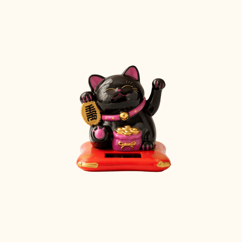 Protective black maneki neko cat japanese with pink accents and golden coin holding both paws raised on red solar base against clean white background