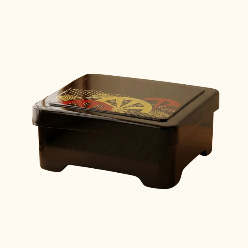 Black sushi bento box with gold with red and gold wheel pattern on neutral background