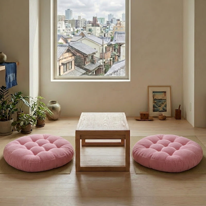Two pink tufted cushions floor Japanese seating sit on either side of a low table with a city skyline view