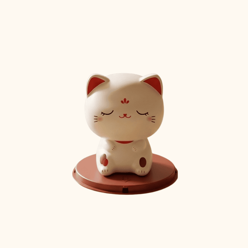 Peaceful cute japanese maneki neko with closed eyes in meditation pose on terracotta base displayed on white background