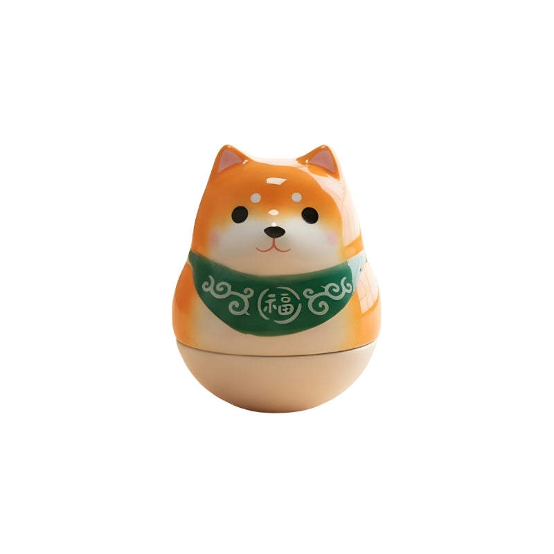 Daruma doll statue with green fortune collar and alert expression
