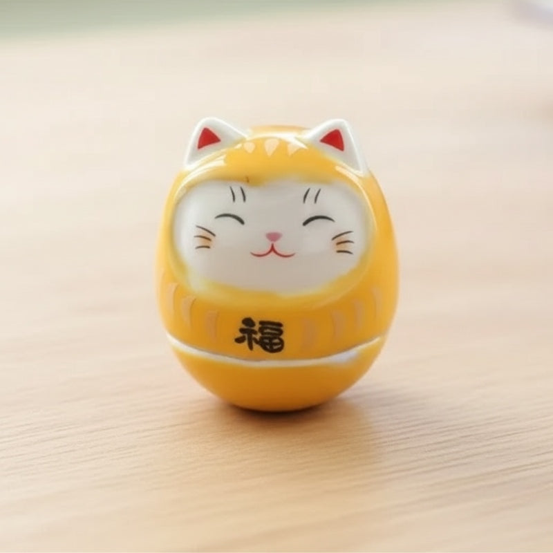 Cheerful daruma lucky cat in bright yellow with cat ears and happiness symbol displayed on wooden surface