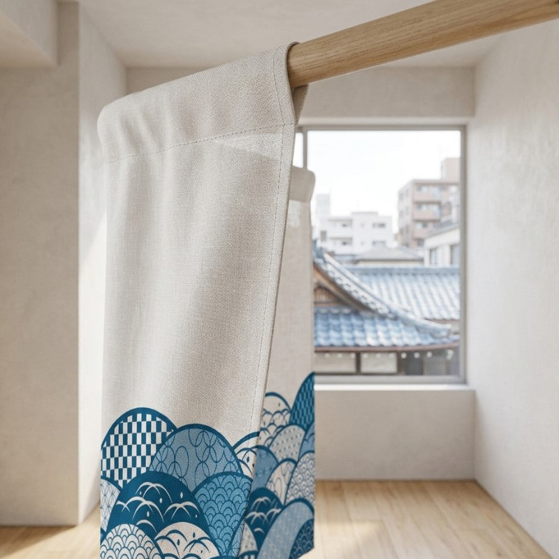 Single panel doorway curtain japanese noren with blue seigaiha wave pattern on cream linen hanging on wooden rod in bright minimalist Japanese apartment with city rooftop view