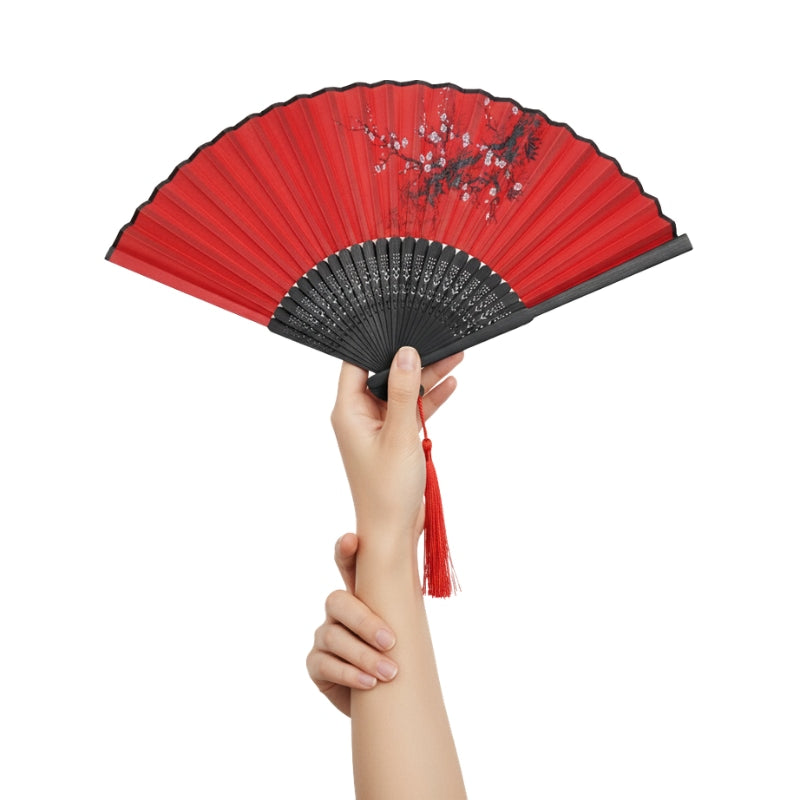 Hand holding crimson fan dance japanese with black lacquered frame and plum blossom design against clean white background with red tassel