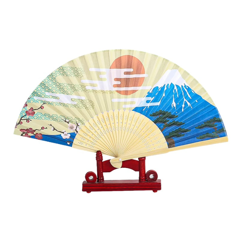 Decorative fan japanese paper with Mount Fuji red sun and cherry blossoms displayed on red wooden stand showcasing traditional landscape artwork