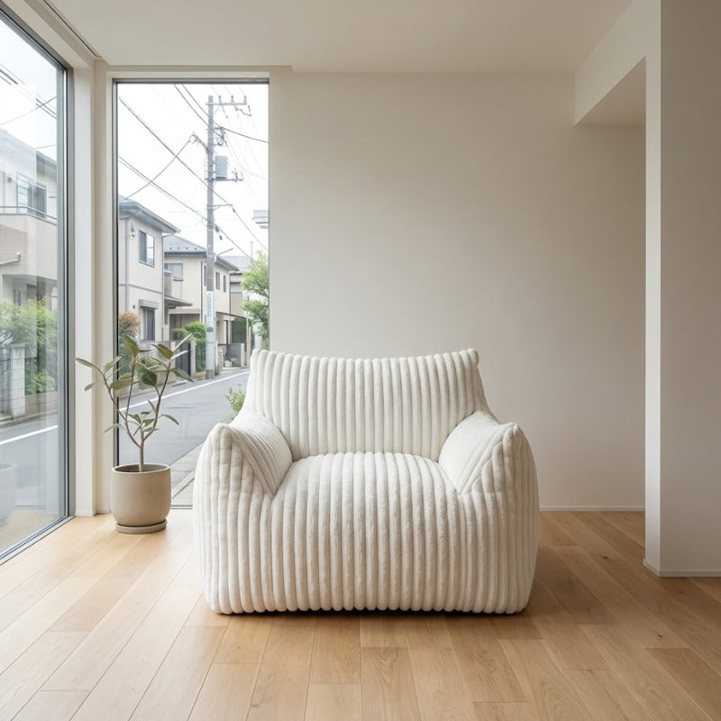 Floor sofa japanese armchair with ribbed white fabric and curved armrests on light wood flooring near window