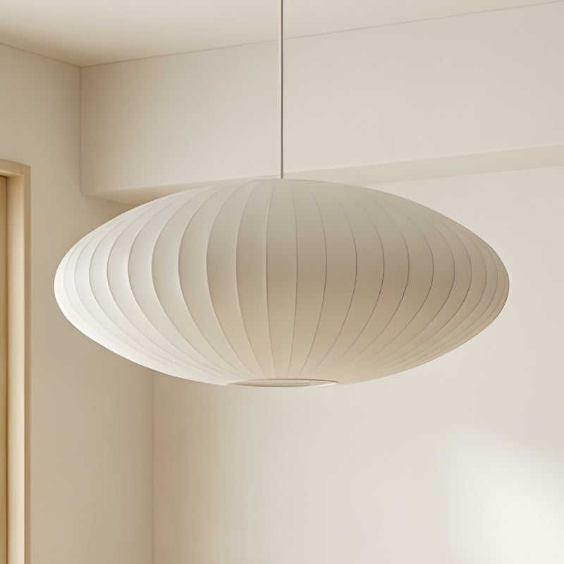 Oval japandi lamp with pleated white shade suspended in minimalist room with neutral beige walls