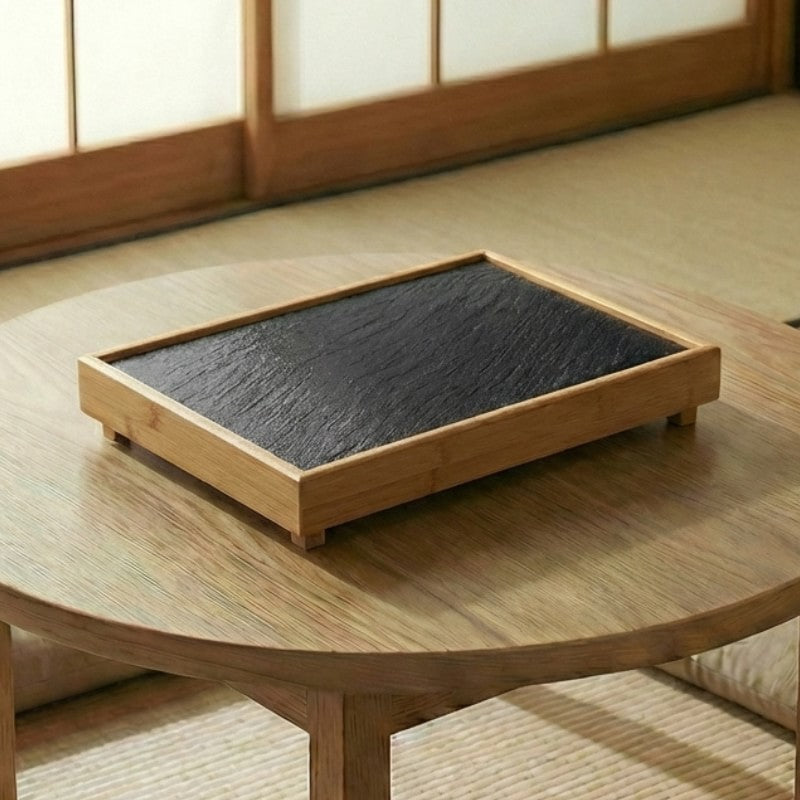 Japanese BBQ plate black slate stone in bamboo frame on round wooden table in minimalist tatami room with shoji screens