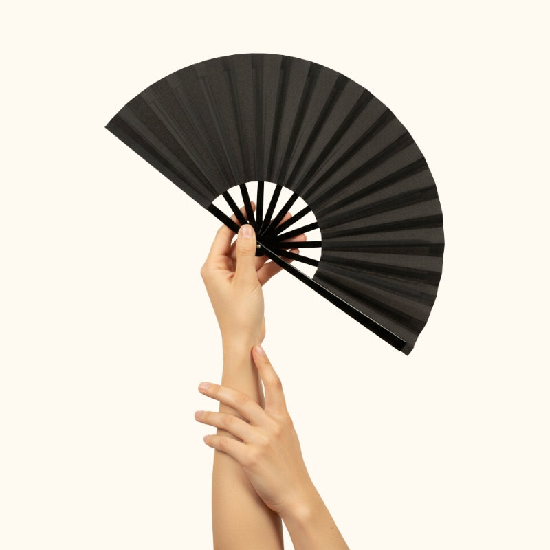 Refined japanese big fan in matte black held with both hands against minimalist white backdrop showcasing graceful folding design