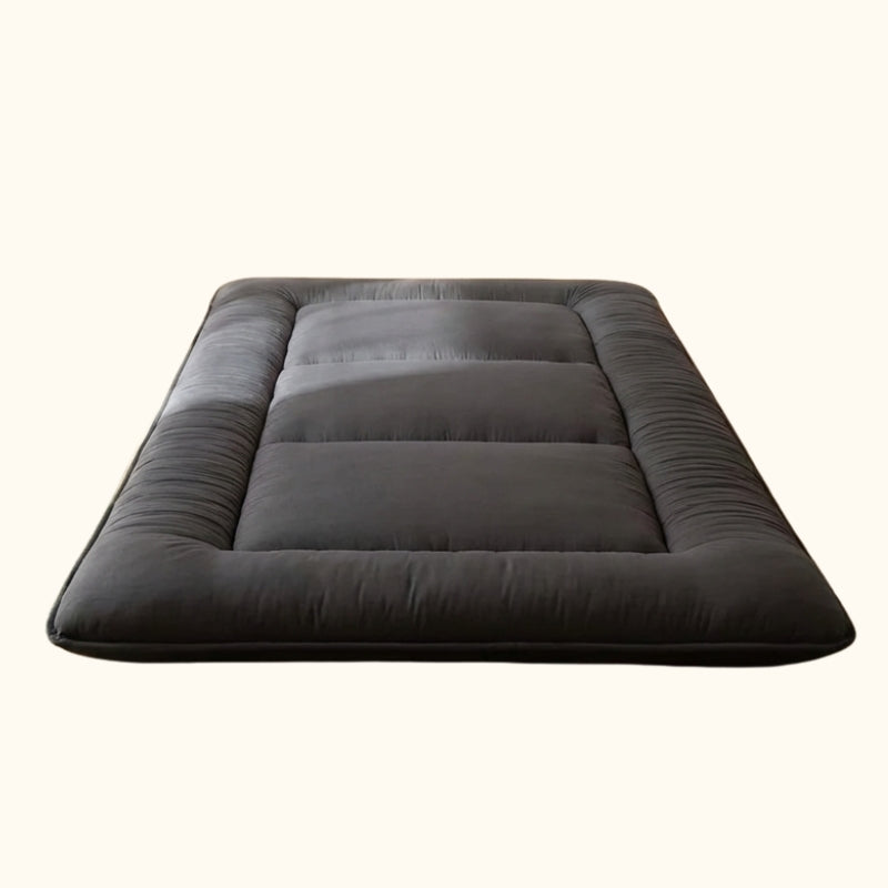 Elegant japanese black futon bed with thick quilted borders and sectioned padding displayed on clean white background showing quality construction