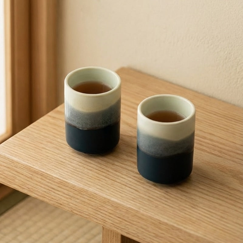 Japanese ceramic tea cup duo featuring sea to sky gradient with tea on wooden surface in natural light