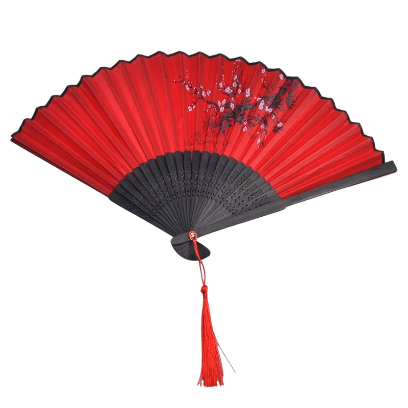 Traditional japanese dance fan fully opened displaying crimson paper surface with plum blossom artwork and carved black bamboo frame on white background