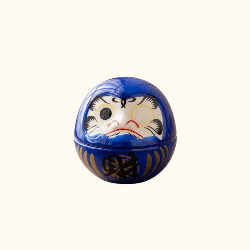 Vibrant japanese daruma blue with gold prosperity character and blank eyes for wish making on clean white background