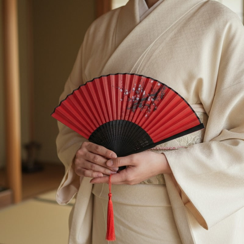 Japanese fan dance with red plum blossoms held gracefully by person wearing cream kimono with obi in traditional interior setting