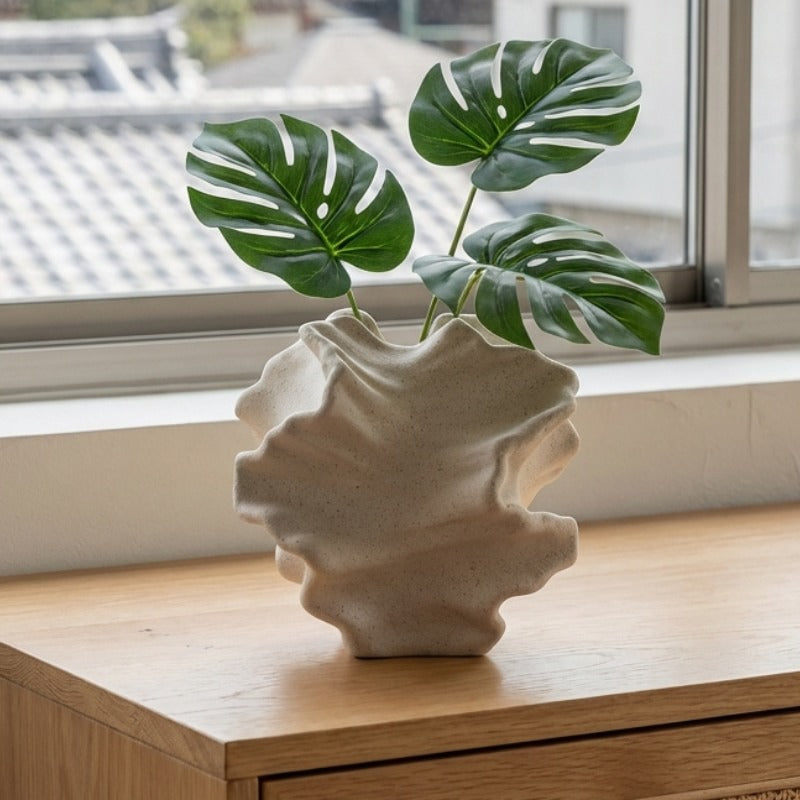 Modern japanese floral vase holding monstera leaves on wooden shelf overlooking traditional rooftops