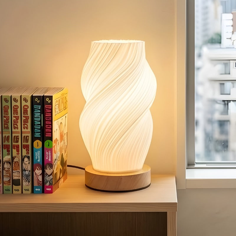 Modern japanese lamp table with twisted spiral shade casting warm light next to manga collection on shelf
