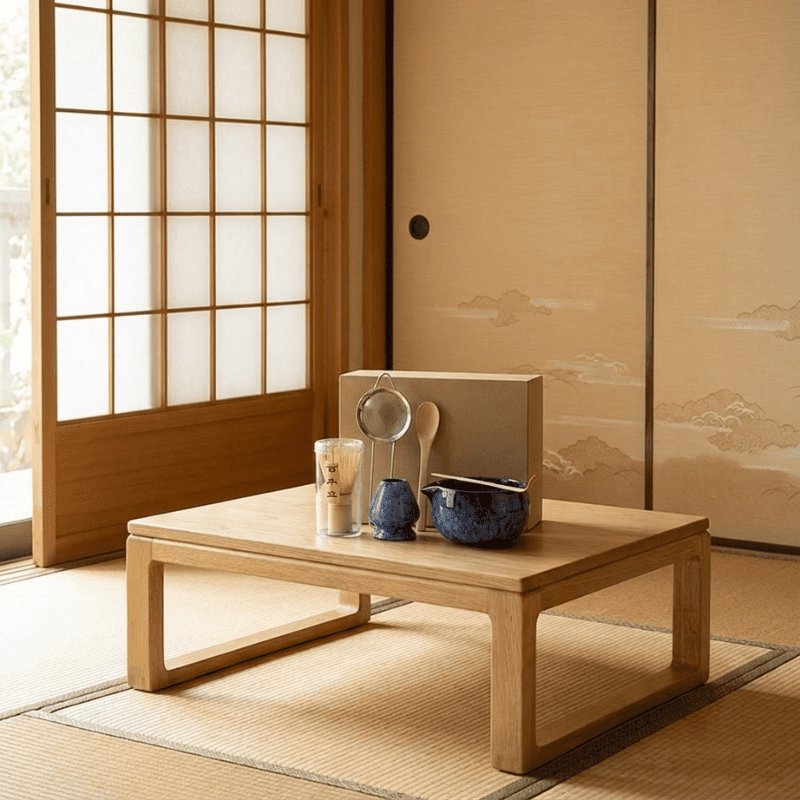 Traditional matcha whisk set blue glazed bowl arranged on low wooden table beside shoji screen and mountain art backdrop