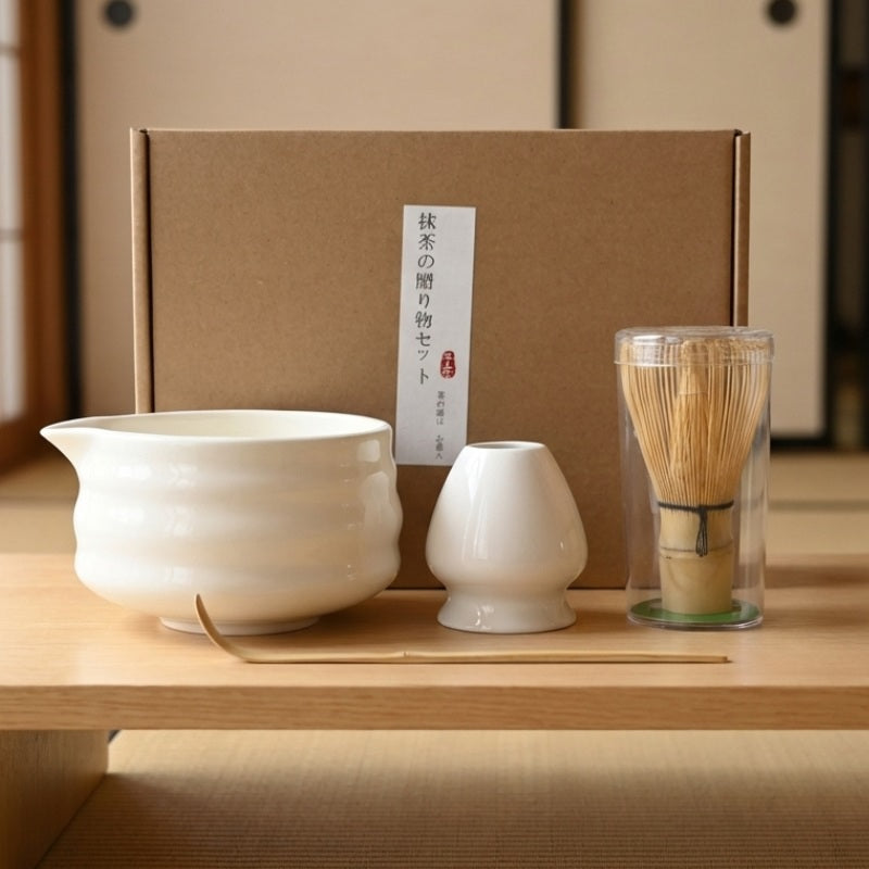 Complete japanese matcha whisk set with white porcelain bowl bamboo tools and kraft gift box displayed on natural wood shelf