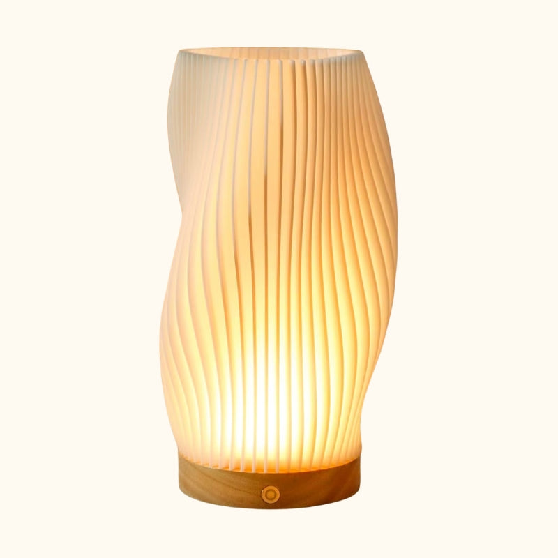 Japanese modern lamp white sculptural pleated shade with hourglass silhouette on natural wood base displayed on neutral background