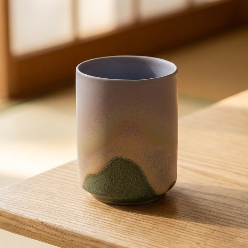 Japanese tea cup set featuring painted mountain peak on wooden table in warm natural daylight