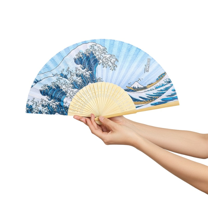 Beautiful kanagawa hand fan featuring iconic wave pattern held with both hands against minimalist white background highlighting intricate blue wave details