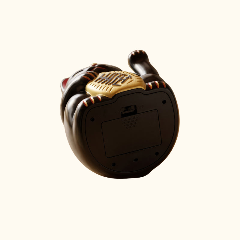 Underside of the black Maneki Neko lucky cat statue showing its battery compartment and power switch.