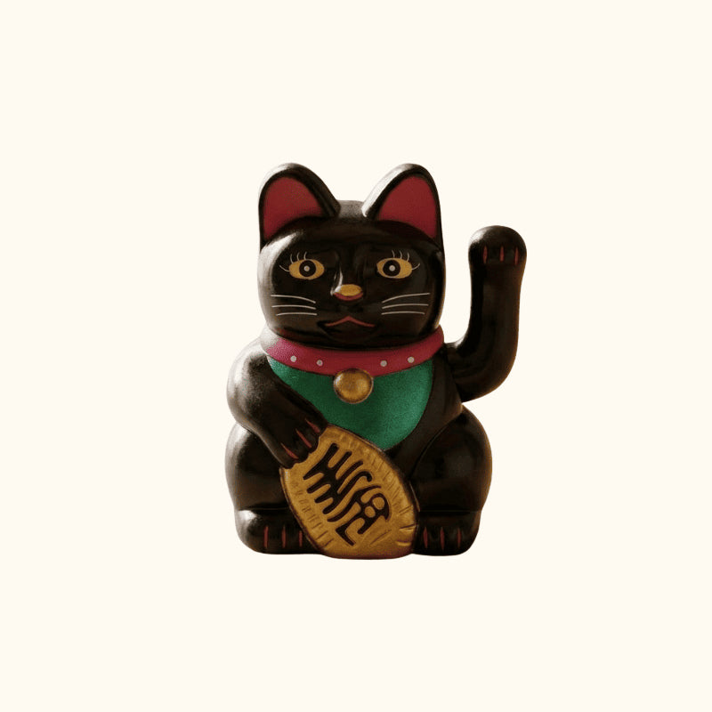 Black lucky Maneki Neko cat statue holding a gold coin, with a raised waving paw and traditional red collar.
