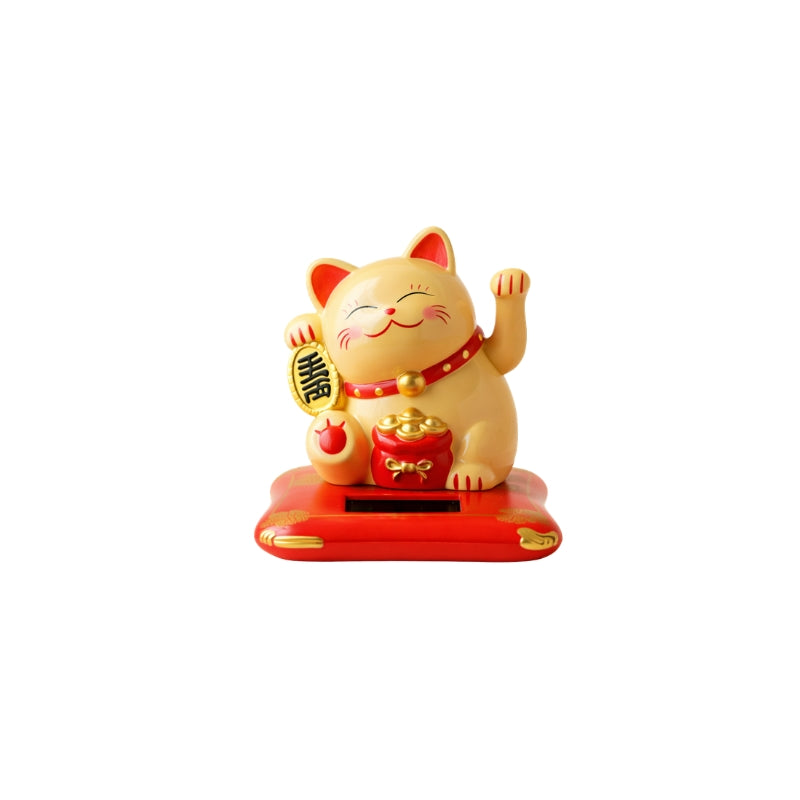 Beige maneki neko cat japanese figurine with both paws raised holding coin and bells on red solar base isolated against white background view