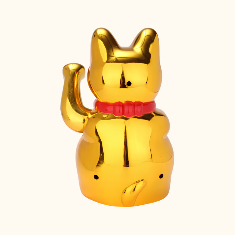Rear view of a gold Maneki Neko cat statue with a reflective metallic finish, raised waving paw and red collar.