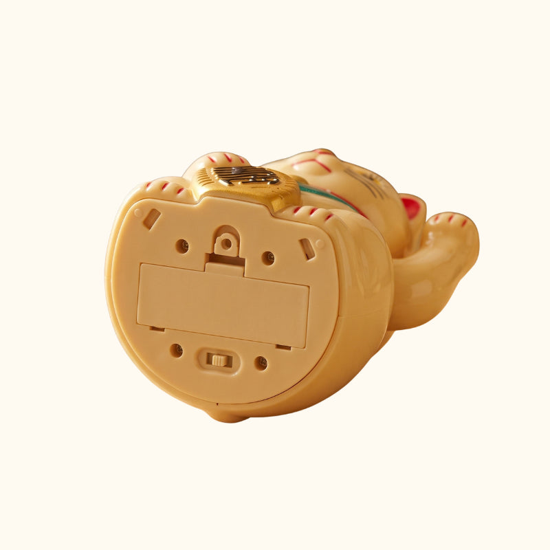 Base of a golden Japanese Maneki Neko figurine showing the battery compartment and on-off switch.