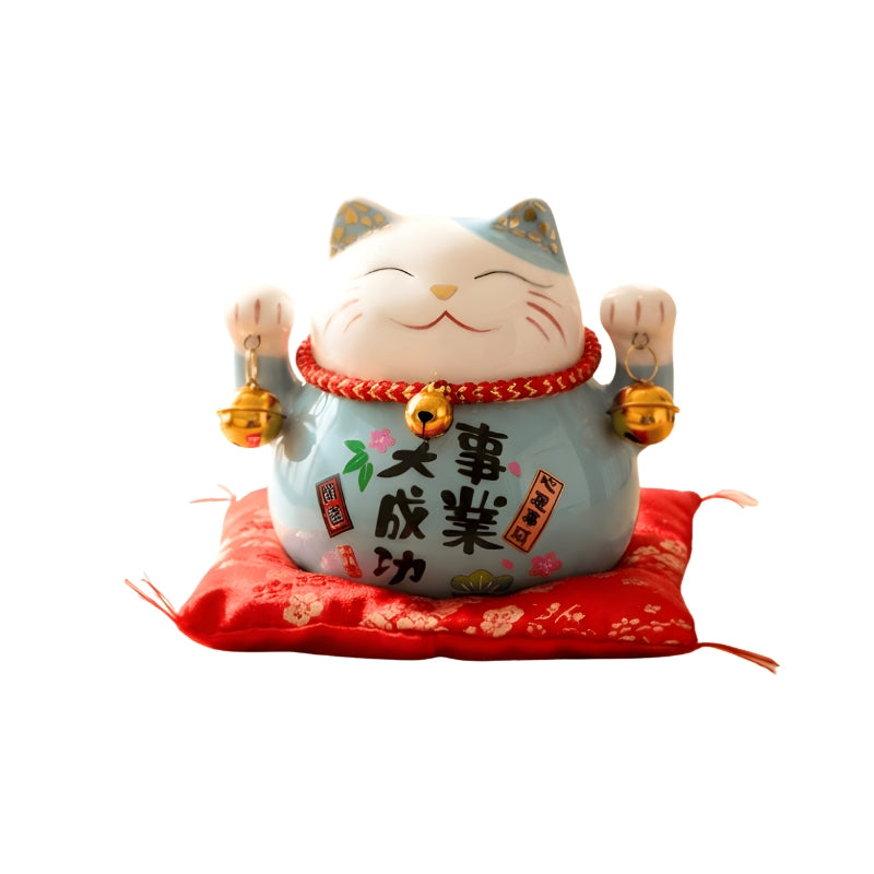 Prosperous maneki neko lucky cat japanese figurine with kanji calligraphy and golden bells displayed on red floral cushion against clean white background