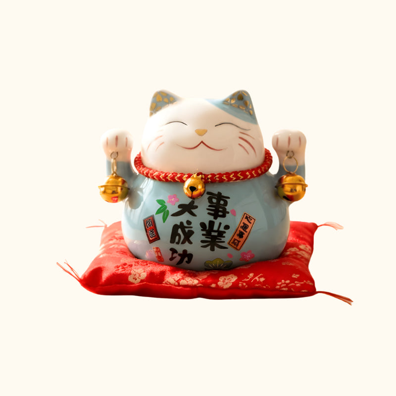 Blue Maneki Neko Lucky Cat Japanese ceramic figurine with raised paws, golden bells and red cushion