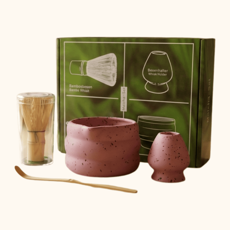 Complete pink matcha gift japanese set including ceramic bowl and bamboo tools with green illustrated gift box on clean white background