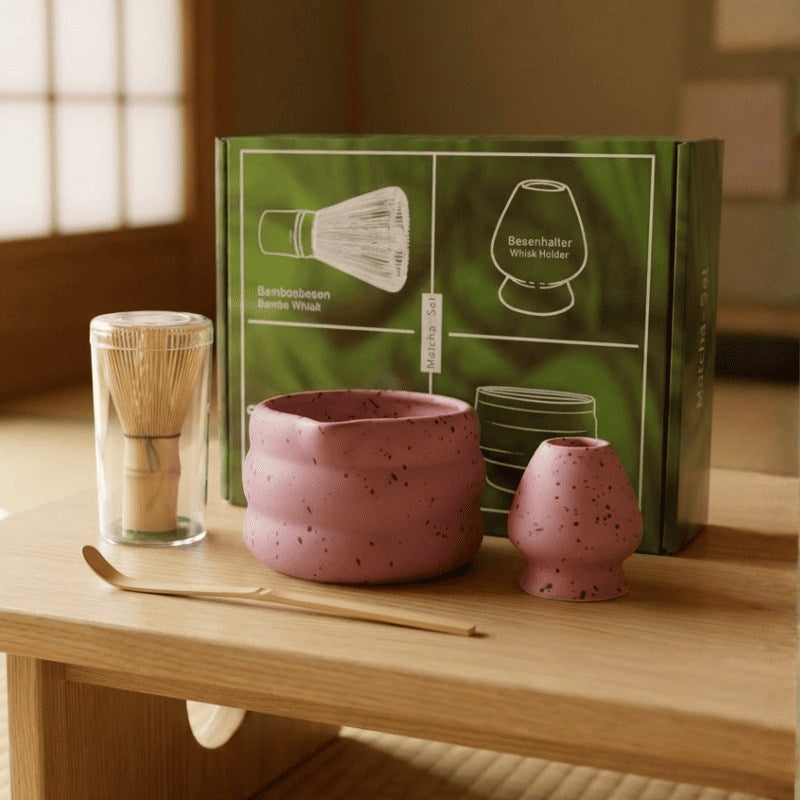Soft pink matcha gift set with bamboo accessories and green gift packaging positioned on wooden table catching warm window light in Japanese interior