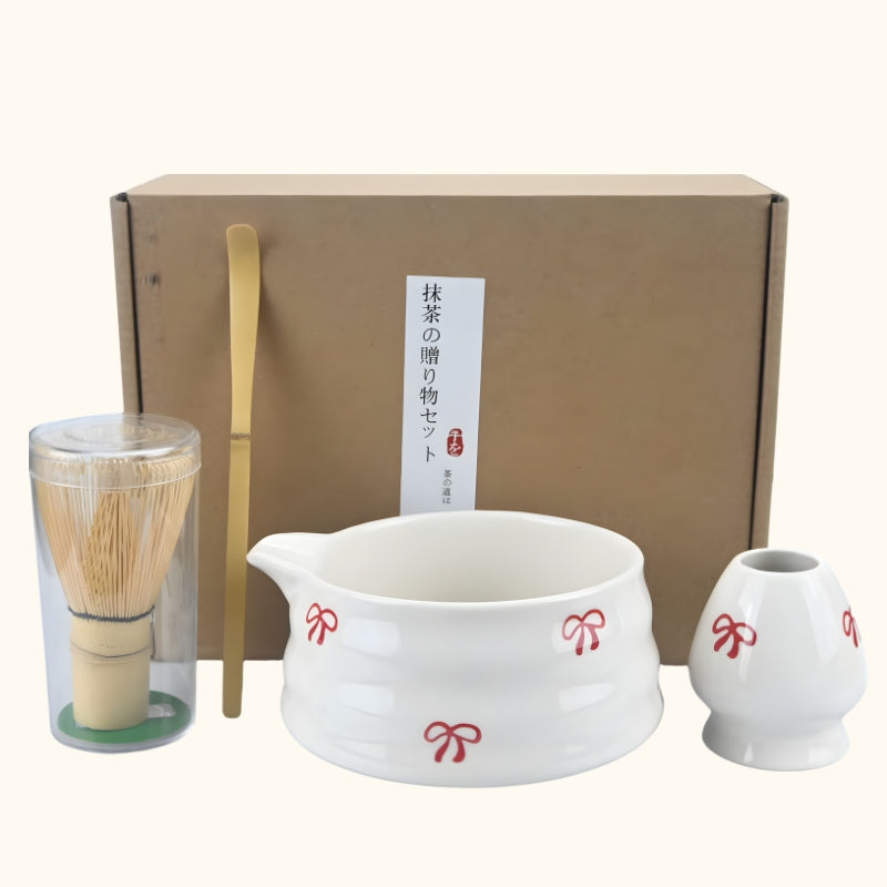 Matcha set green tea white porcelain bowl with red bows chasen whisk and chashaku displayed with kraft gift box on neutral background