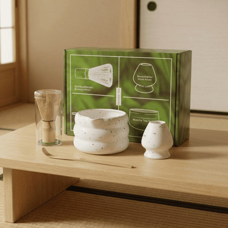 Speckled white ceramic matcha tea set white with bamboo whisk and green gift box displayed on wooden table in traditional Japanese interior