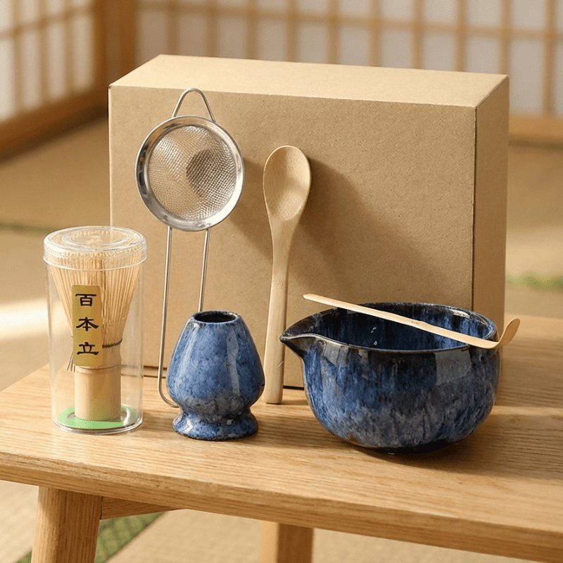 Complete japanese matcha whisk set in deep blue ceramic with bamboo whisk and tools displayed beside kraft gift box on wooden table