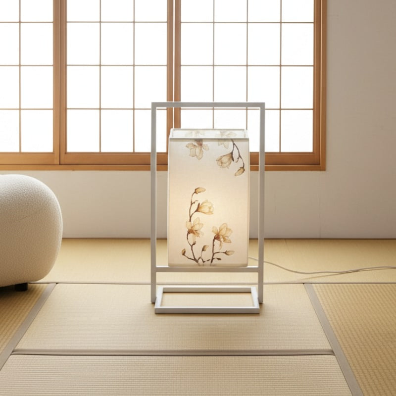 Serene modern japanese table lamp with delicate flower stems on white cloth shade suspended in aluminum frame near traditional shoji window