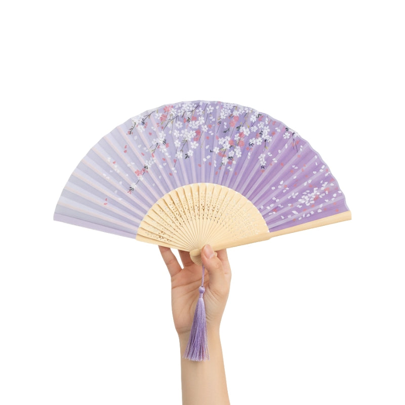 Person wearing cream kimono holding paper japanese folding fan with lavender background and white sakura in traditional interior setting