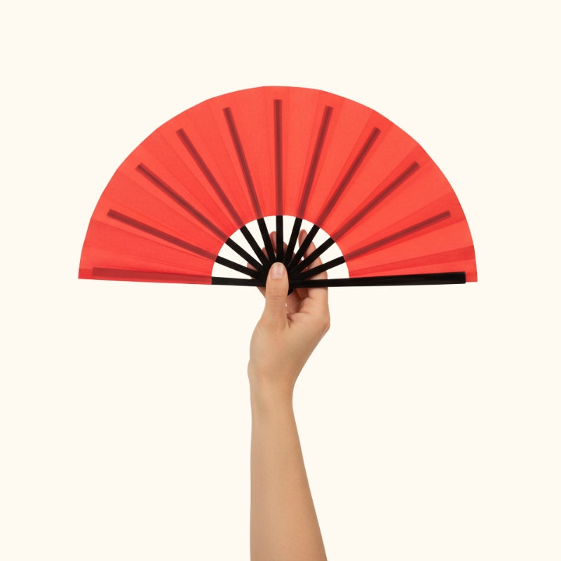 Beautiful red fan japanese with gradient coral shades held delicately in hand against minimalist white background highlighting fine details