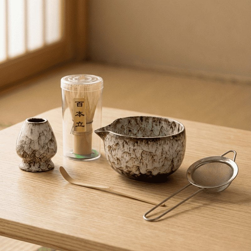 Traditional set for matcha in earthy brown tones with ceramic bowl and bamboo tools on wooden table catching soft natural daylight