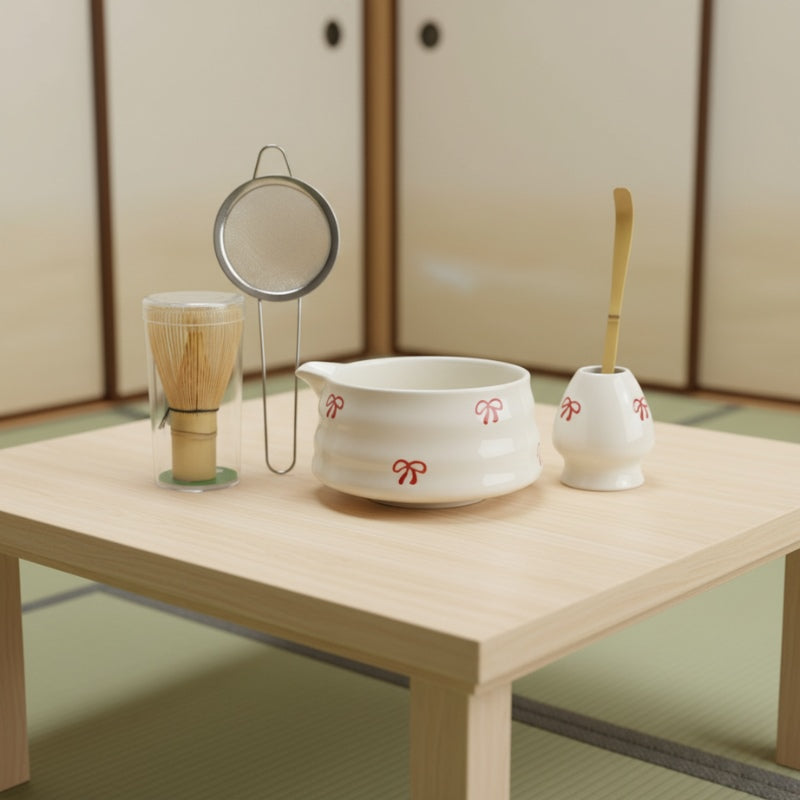 Set matcha green tea white porcelain bowl with red bows bamboo chasen sieve and golden scoop on low table in tatami room