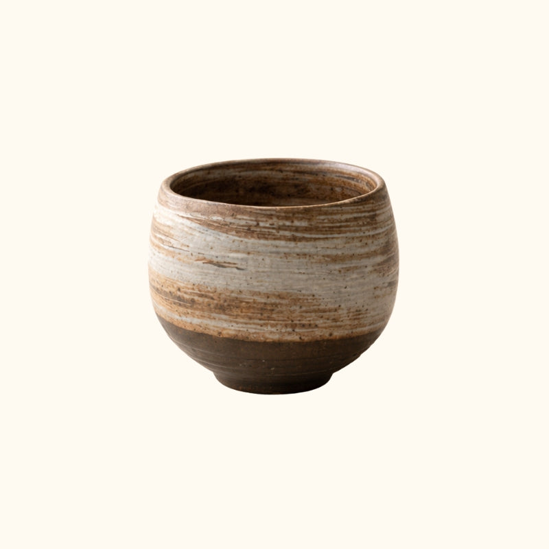 Tea japanese pot pottery in round form with horizontal earth bands and dark base on clean white background