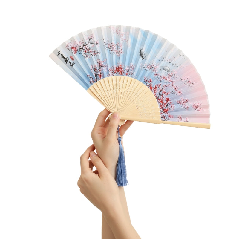 Elegant vintage hand fan japanese style with gradient cherry blossom design held gracefully showing natural bamboo frame and blue silk tassel